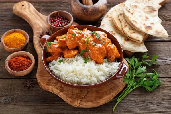 Pyszne chicken tikka masala z ryżem, podane z chlebkiem naan i przyprawami.